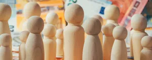 kleine Holzfiguren vor Geldscheinen