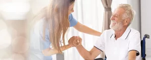 Pflegerin mit Mann im Rollstuhl