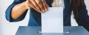 Frau wirft Wahlkuvert in Wahlurne