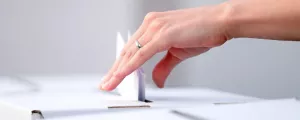Frau wirft Kuvert in eine Wahlurne