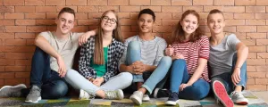 Gruppe von Jugendlichen sitzt vor einer Mauer