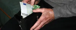 Mann zieht Geldschein aus Geldbörse