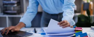 Frau arbeitet mit einem Stapel Papierakten, um Dokumente zu suchen