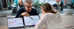 Mann und Frau arbeiten gemeinsam an 2 Laptops