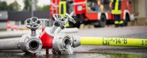 Feuerwehrschlauch und Auto im Hintergrund