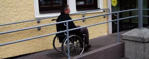 Mann mit Rollstuhl auf Rampe