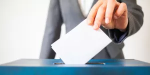 Frau wirft Kuvert in Wahlurne