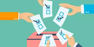 Hände mit Stimmzetteln und Wahlurne