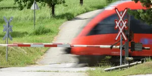Zug fährt bei Bahnschranken vorbei