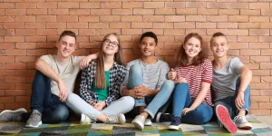 Gruppe von Jugendlichen sitzt vor einer Mauer