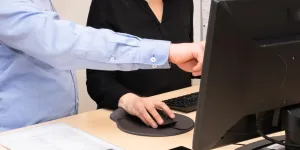a man and a woman working together on a pc, man pointing at screen