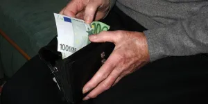 Mann zieht Geldschein aus Geldbörse