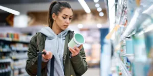 Frau vergleicht im Supermarkt Preise
