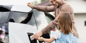 Mann und Kind tanken E-Auto