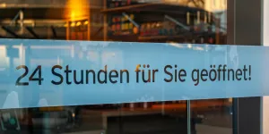 Schaufenster von Ladengeschäft mit Schild „24 Stunden für Sie geöffnet“