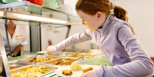 Kind nimmt sich Essen von einem Buffetwagen