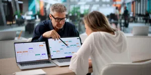 Mann und Frau arbeiten gemeinsam an 2 Laptops