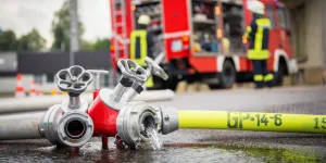 Feuerwehrschlauch und Auto im Hintergrund