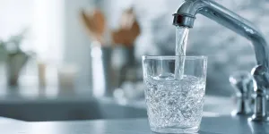 Wasser fließt aus einer Armatur in ein Glas