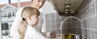 Mutter und Tochter trinken von der Wasserleitung
