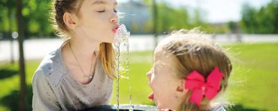 2 Mädchen bei einem Trinkwasserbrunnen