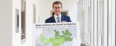 Wirtschafts- und Raumordnungs-Landesrat Markus Achleitner mit einer Karte der beiden bereits bestehenden Grünzonen sowie der derzeit in Umsetzung befindlichen regionalen Grünzone in Wels-Grieskirchen.