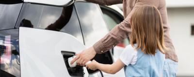 Mann und Kind tanken E-Auto