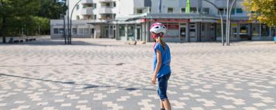 Mädchen skatet auf einem Skateboard auf einem Platz vor einem Hochhaus