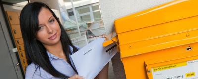 Frau wirft Wahlkarte in Briefkasten ein