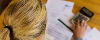 Frau sitzt über Papierwerk mit Lastschriftbescheid