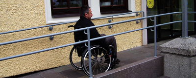 Mann mit Rollstuhl auf Rampe