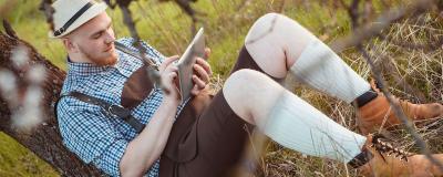 Mann in Lederhose im Wald mit Tablet
