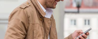 Mann mit Lederjacke schaut auf Smartphone