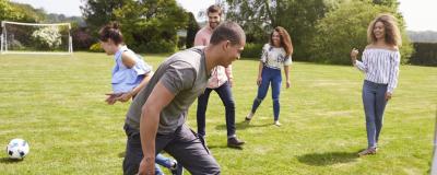 Jugendliche spielen auf Fußballplatz in Alltagsoutfit