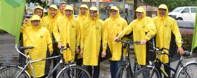 Politiker mit Regenmänteln und als Radfahrer