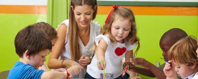 Kindergärtnerin beschäftigt sich mit mehreren Kindern