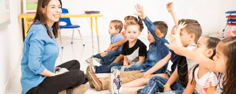 Gruppe voller Kinder zeigt auf und Betreuerin lacht