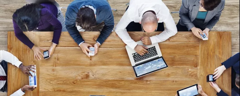 Menschen mit Laptops und Tablets sitzen an einem Tisch