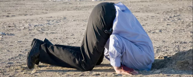 Mann steckt Kopf in den Sand
