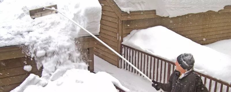 Mann räumt Schnee von einem Haus