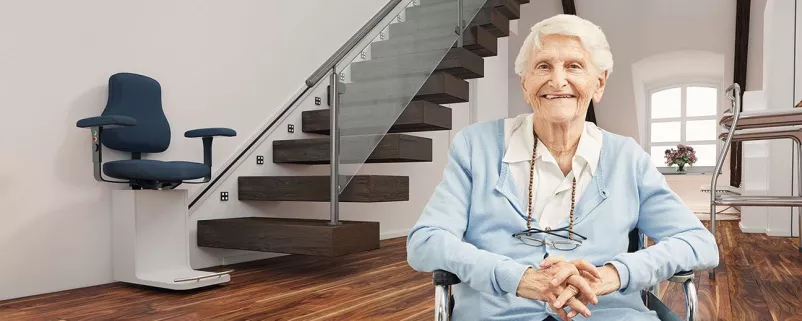 Seniorin im Rollstuhl vor Treppenlift zu Hause 