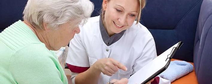 Seniorin und Pflegerin sitzen beieinander