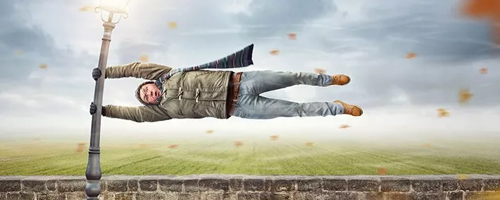 Mann im Sturm hängt an einer Laterne