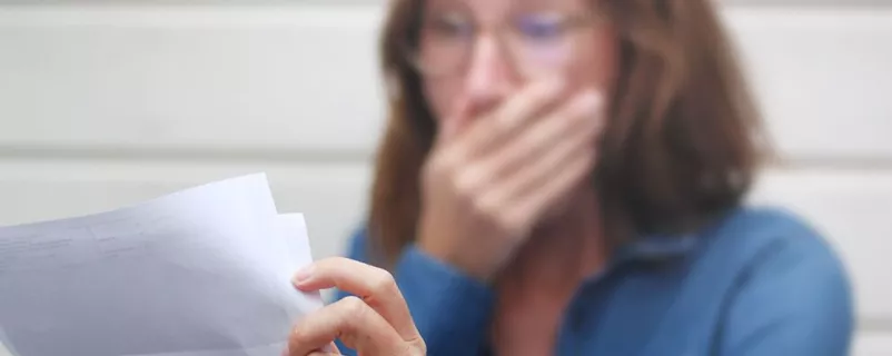 Frau ist schockiert beim Lesen einer Rechnung