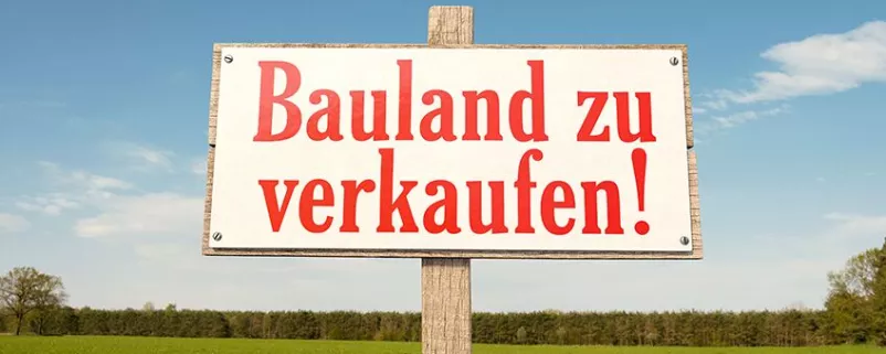 Schild auf der grünen Wiese: Bauland zu verkaufen!