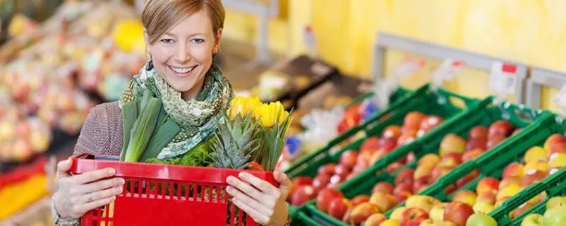 glückliche junge frau beim einkauf im supermarkt