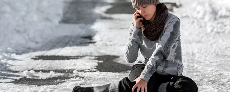Frau telefoniert, nachdem sie auf Eis ausgerutscht ist