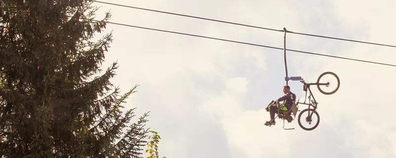 Mann mit Mountainbike auf einem Sessellift