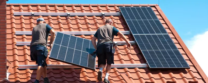 Männer montieren PV-Anlage auf einem Dach