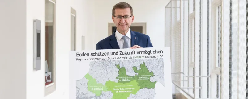 Wirtschafts- und Raumordnungs-Landesrat Markus Achleitner mit einer Karte der beiden bereits bestehenden Grünzonen sowie der derzeit in Umsetzung befindlichen regionalen Grünzone in Wels-Grieskirchen.